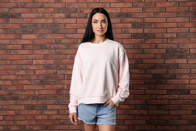 Photo of Portrait of young woman in sweater at brick wall. Mock up for design