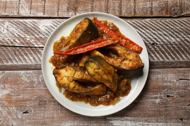 Photo of Tasty Indian fish curry on wooden table, top view