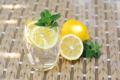 Photo of Refreshing water with lemon and mint on glass table