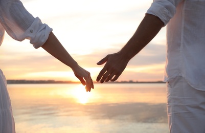 Photo of Man and woman reaching hands to each other at sunset, closeup. Nature healing power