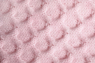 Pink knitted sweater as background, closeup view