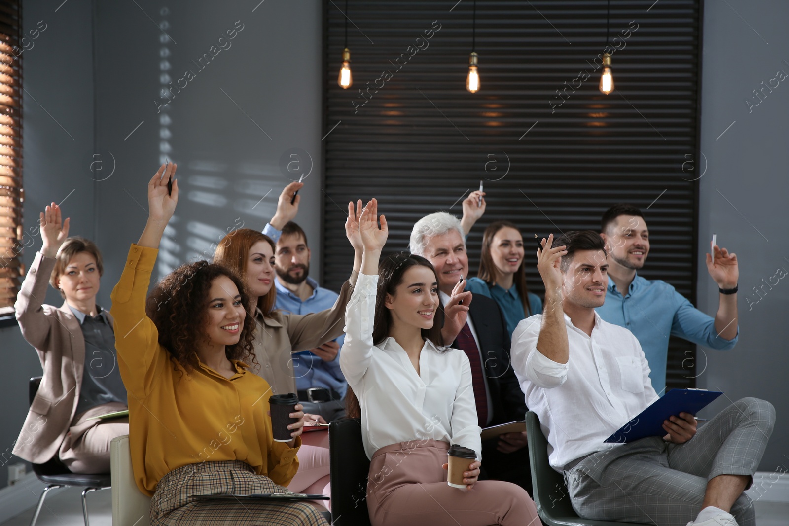 Photo of People raising hands to ask questions at seminar in office