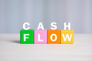 Image of Phrase Cash Flow made with letters and colorful cubes on light background