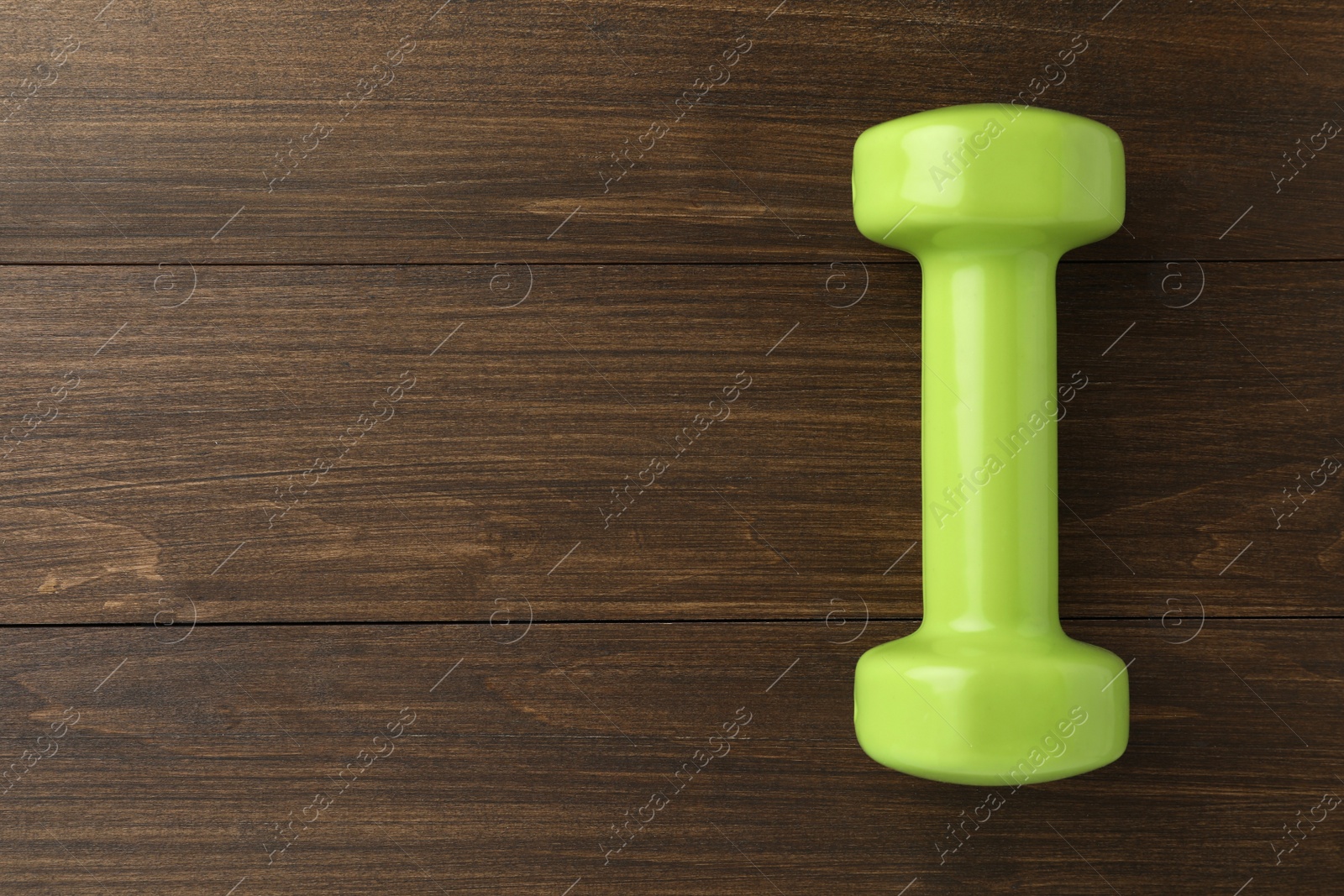 Photo of Light green dumbbell on wooden table, top view. Space for text