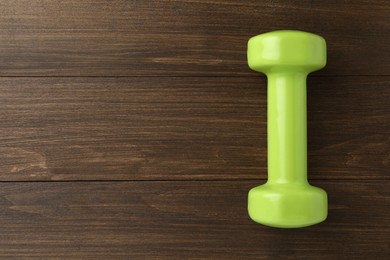 Light green dumbbell on wooden table, top view. Space for text