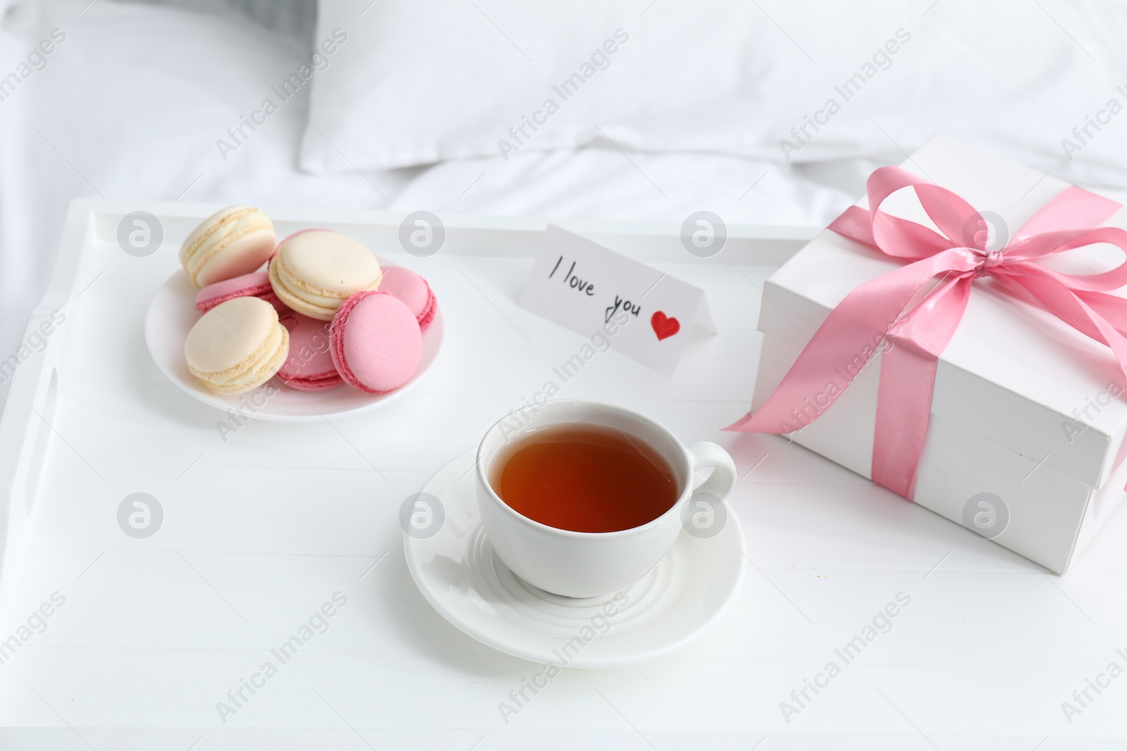 Photo of Tasty breakfast served in bed. Delicious eclairs, tea, gift box and I Love You card on tray