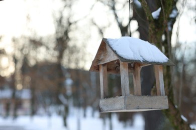 Photo of Wooden birdhouse hanging on tree in park. Space for text