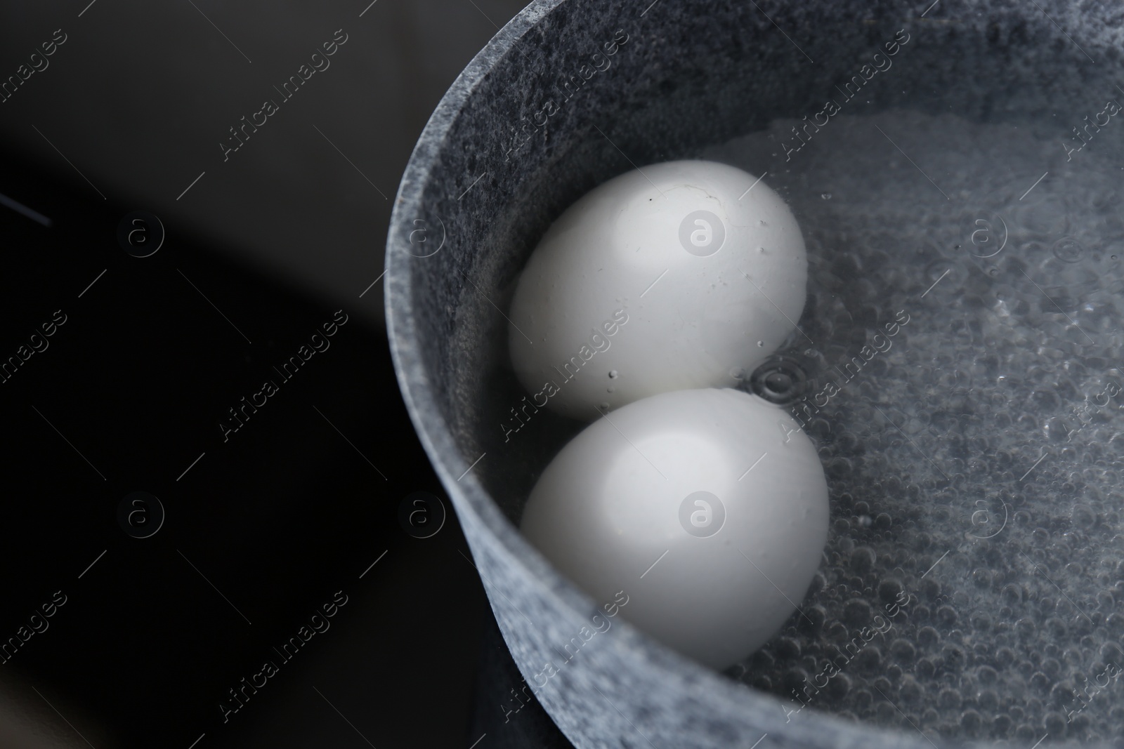 Photo of Chicken eggs boiling in saucepan on electric stove, closeup