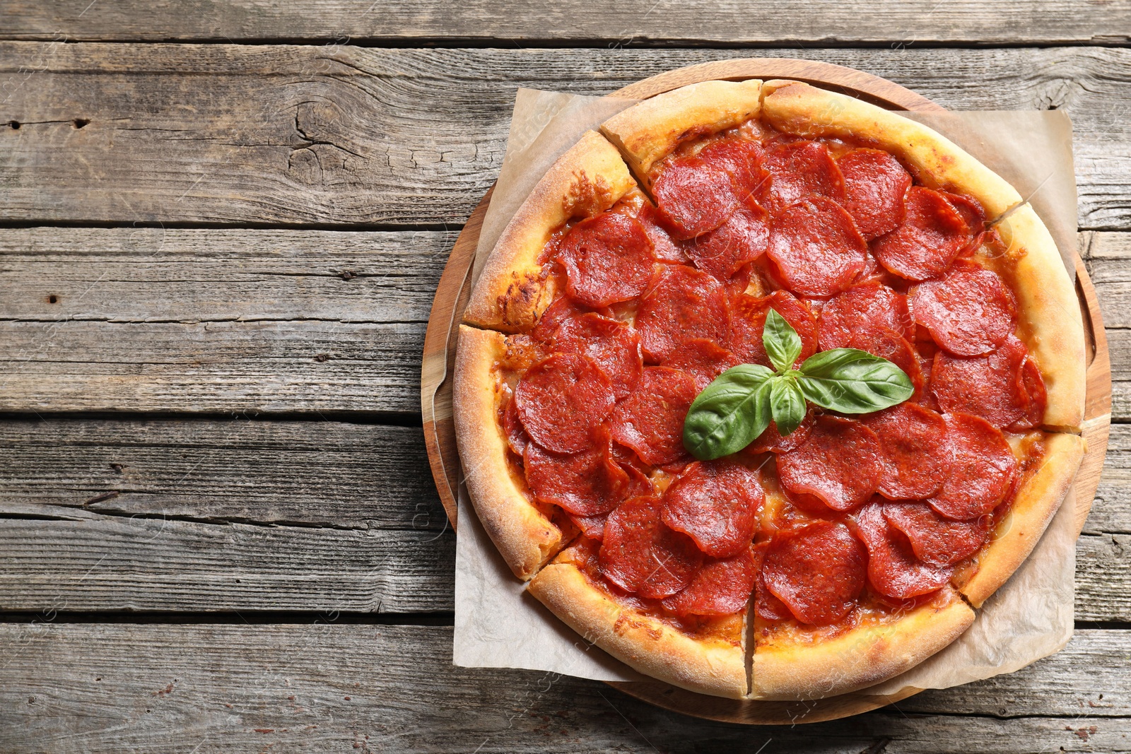 Photo of Tasty pepperoni pizza on wooden table, top view. Space for text