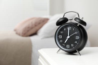 Photo of Black alarm clock on white wooden nightstand in bedroom, space for text