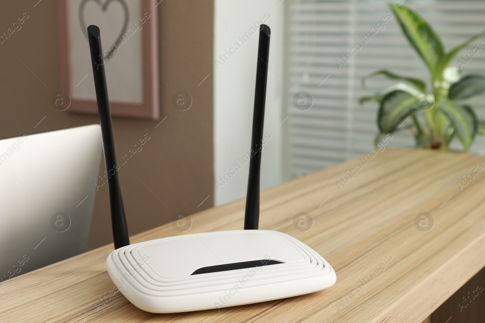 Photo of Modern wi-fi router on wooden counter indoors