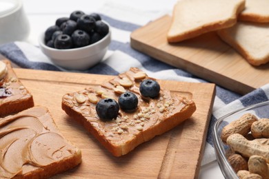 Different tasty toasts with nut butter and products on table, closeup