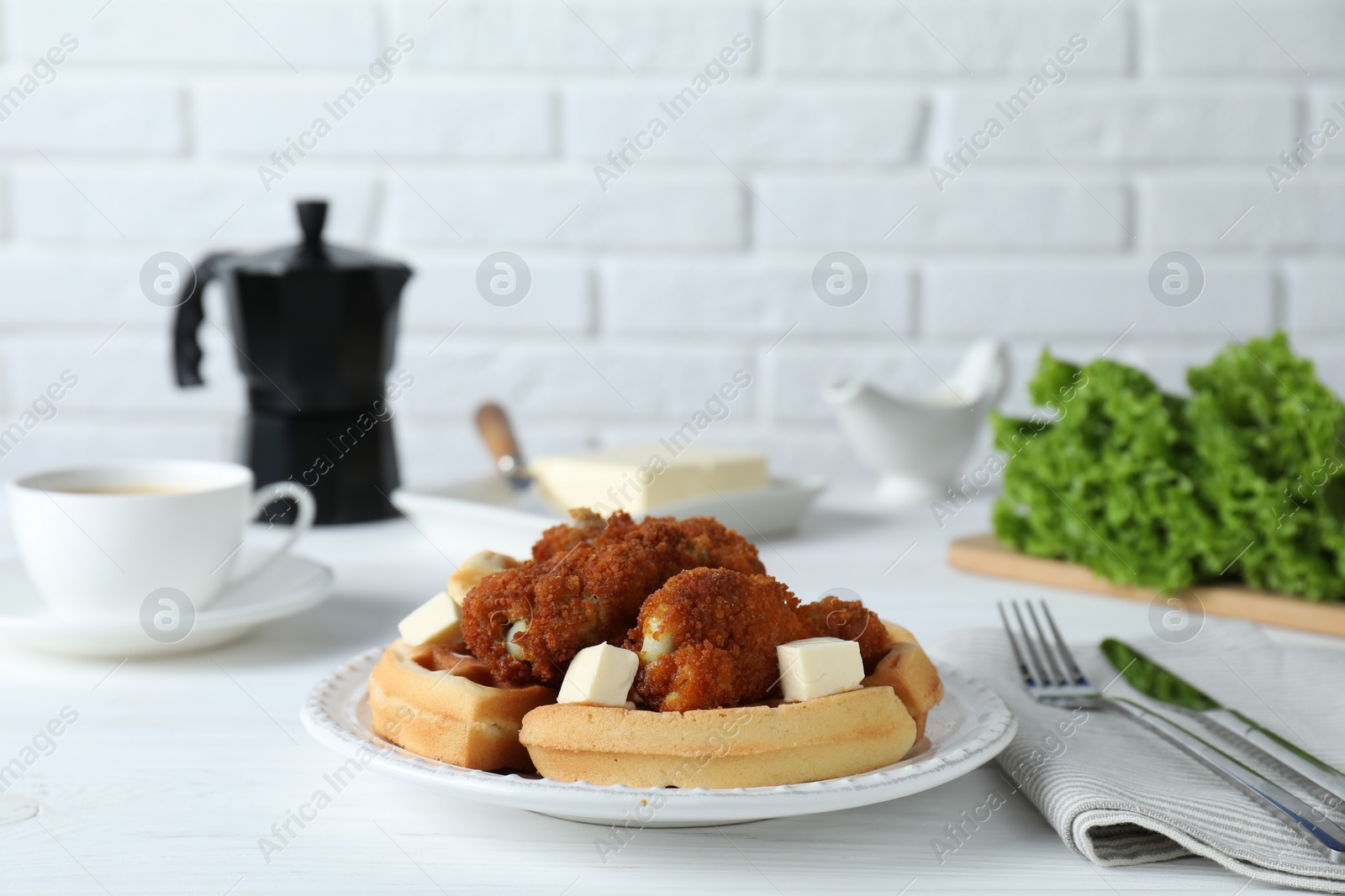 Photo of Delicious Belgium waffles served with fried chicken and butter on white table