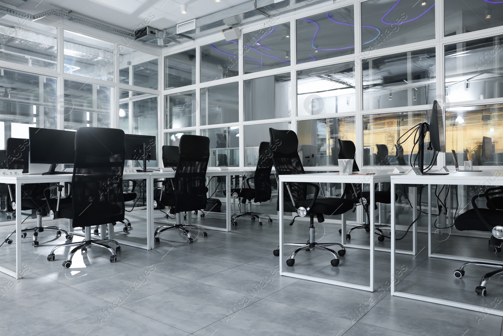 Photo of Stylish interior of open plan office. Workspace with computers, tables and chairs