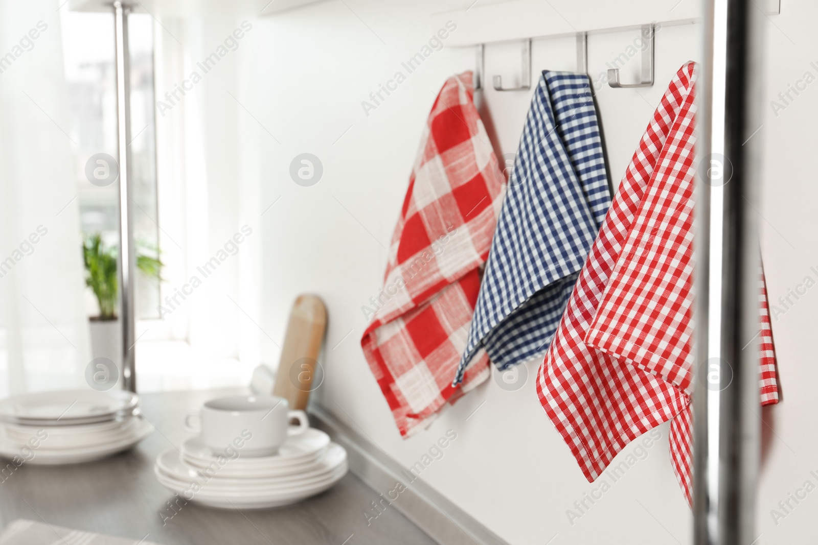 Photo of Different kitchen towels hanging on hook rack indoors