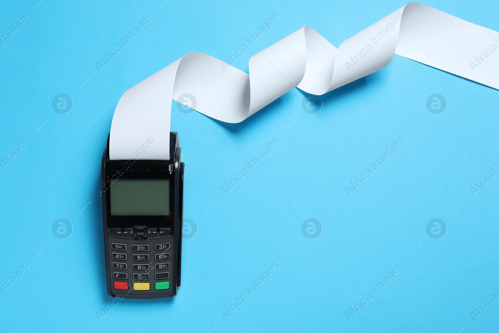 Photo of Payment terminal with thermal paper for receipt on light blue background, top view. Space for text