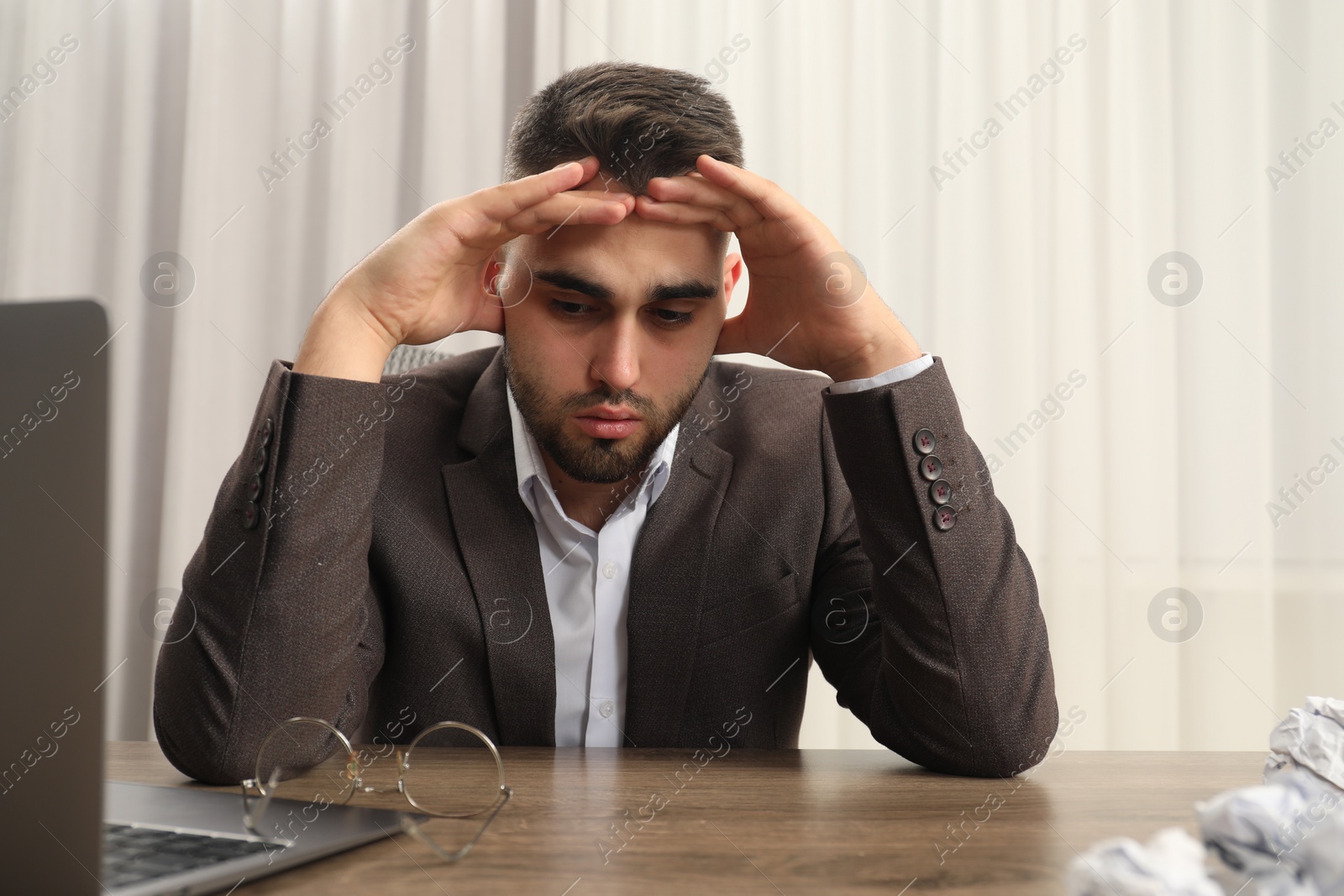 Photo of Tired sad businessman sitting at table in office