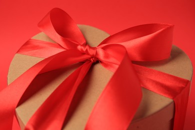 Photo of Beautiful heart shaped gift box with bow on red background, closeup