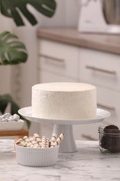 Photo of Delicious cake and sweets for decoration on white marble table in kitchen