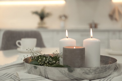 Photo of Beautiful eucalyptus branches, flowers and burning candles on napkin in kitchen. Interior element