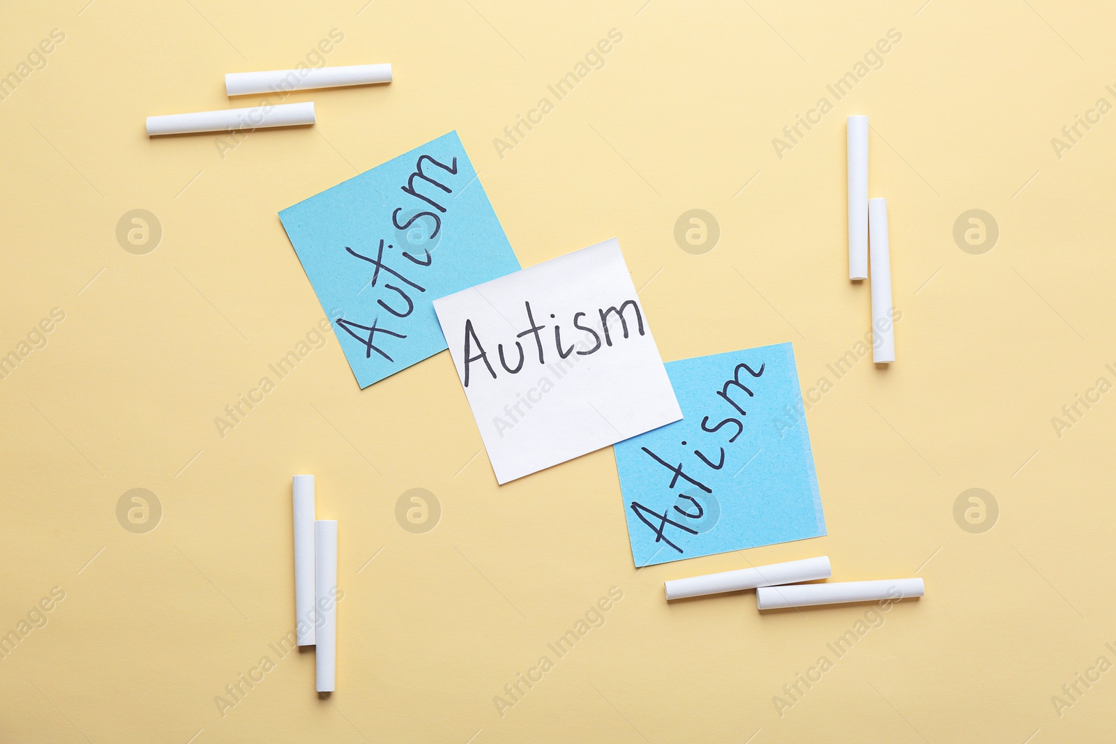 Photo of Sticky notes with word "Autism" on color background, flat lay