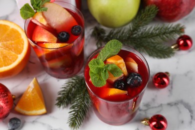 Aromatic Sangria drink in glasses, ingredients and Christmas decor on white marble table