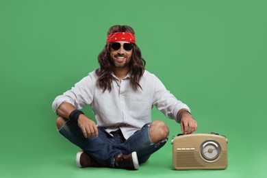 Photo of Stylish hippie man in sunglasses turning on radio receiver against green background