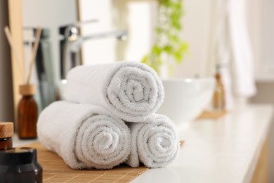 Photo of Rolled soft towels on white table in bathroom. Space for text
