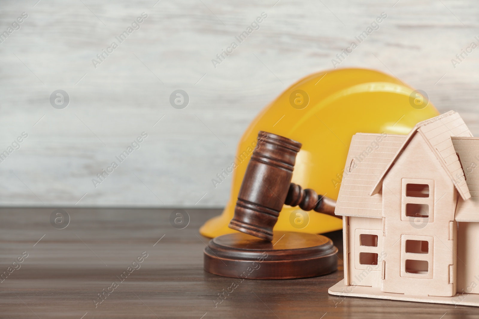 Photo of Construction and land law concepts. Judge gavel, hardhat with house model on wooden table, space for text