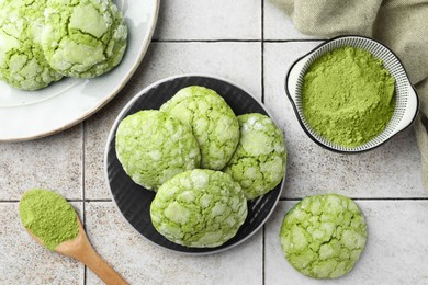 Tasty matcha cookies and powder on tiled table, flat lay