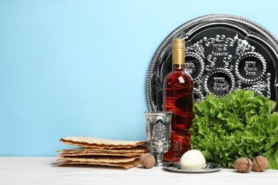 Photo of Symbolic Passover (Pesach) items on wooden table against color background, space for text