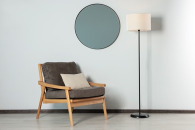 Photo of Stylish round mirror on white wall over armchair in room