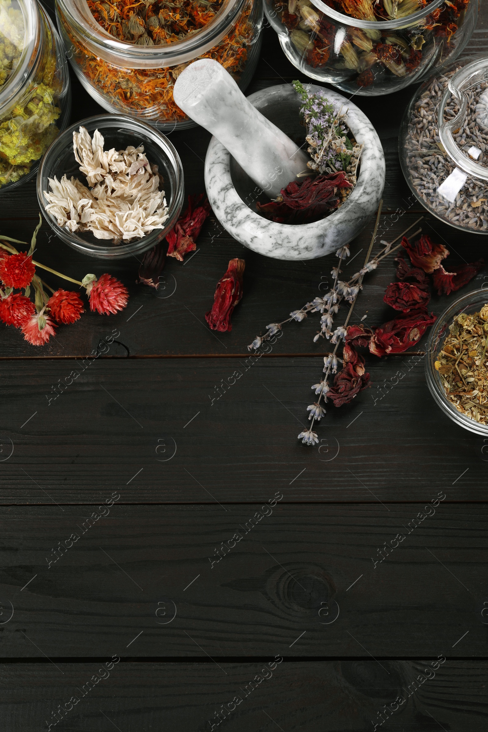 Photo of Mortar with pestle and many different herbs on wooden table, flat lay. Space for text