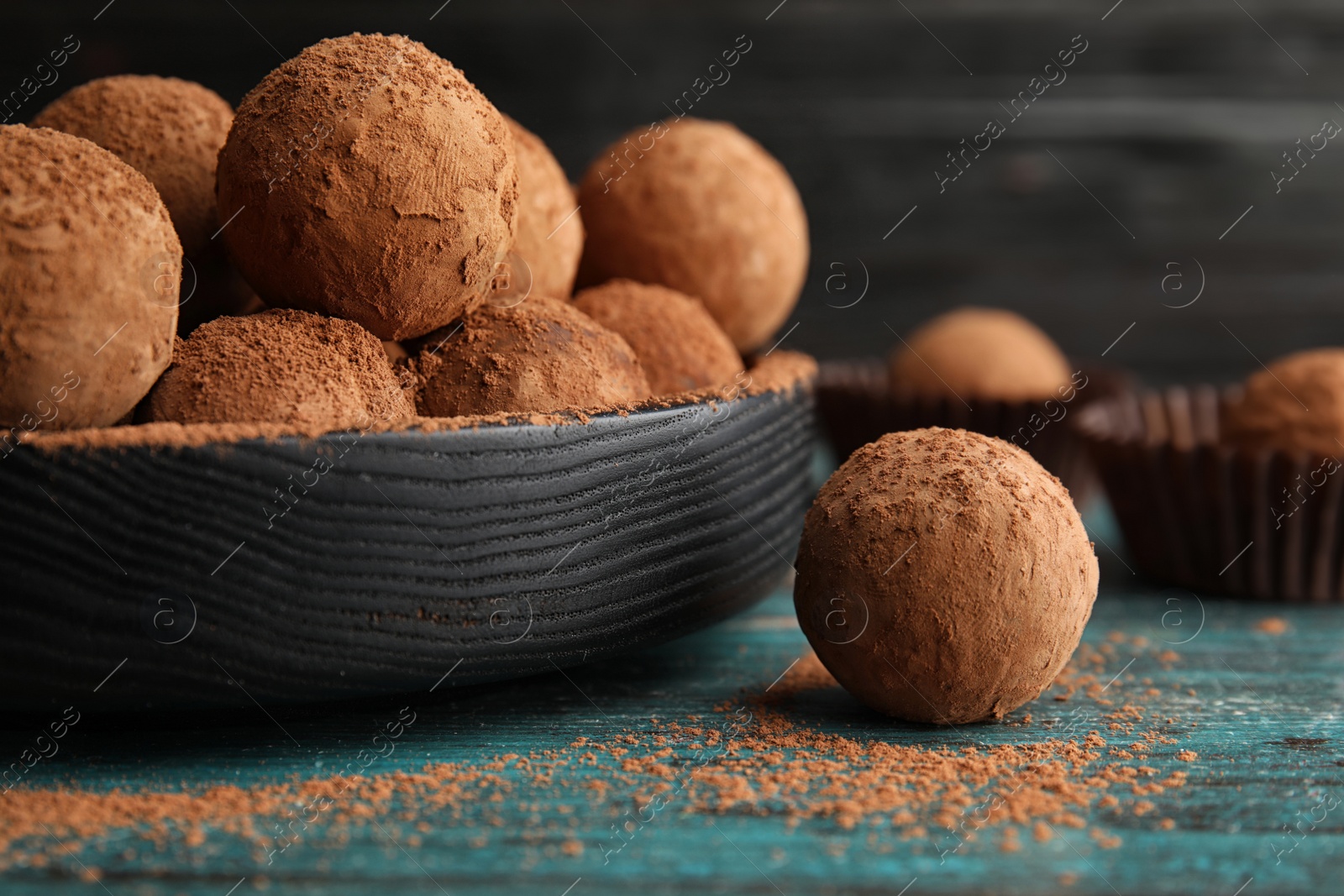 Photo of Plate of chocolate truffles on wooden table, closeup