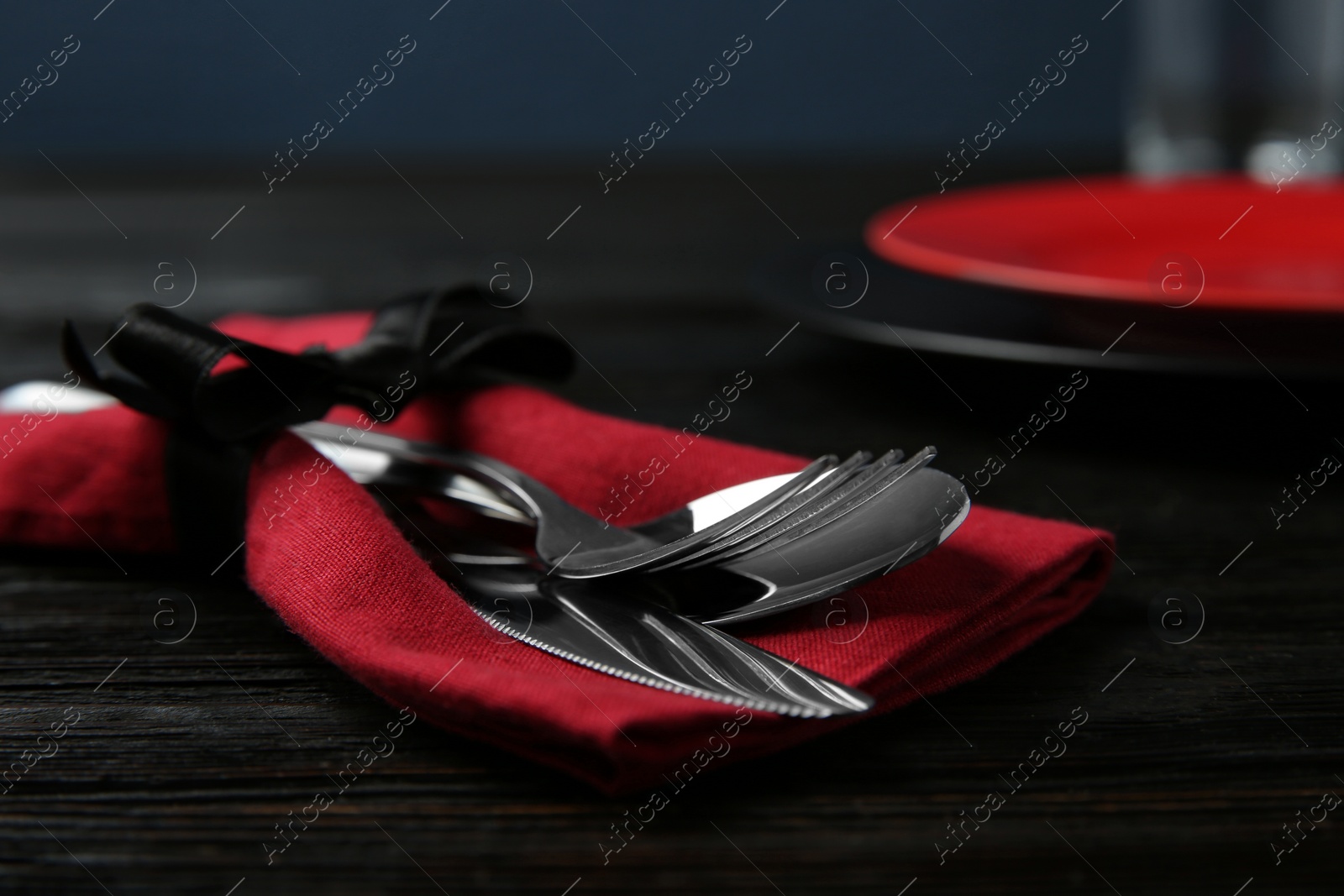 Photo of Cutlery set and dishware on black wooden table, closeup