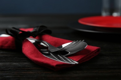 Photo of Cutlery set and dishware on black wooden table, closeup