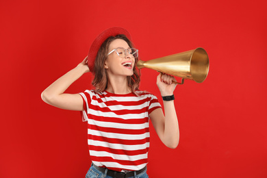 Young woman with megaphone on red background