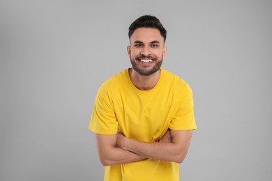 Handsome young man laughing on grey background