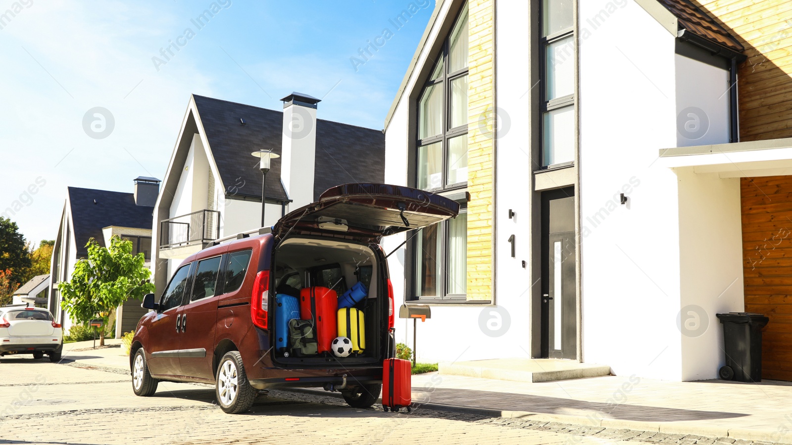 Photo of Car with suitcases in trunk near modern house outdoors. Moving day