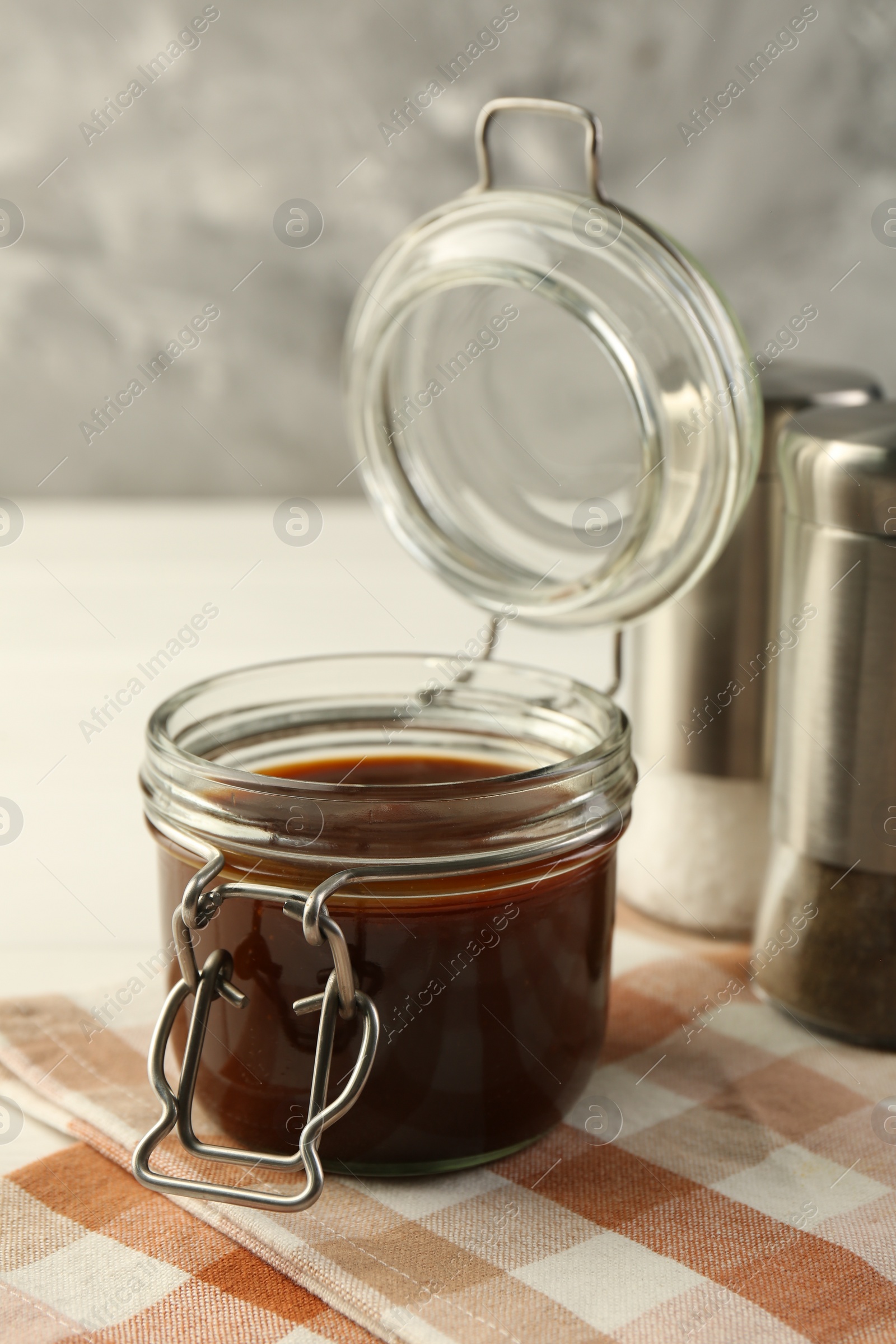 Photo of Tasty barbecue sauce in glass jar on table, closeup