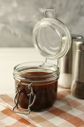 Tasty barbecue sauce in glass jar on table, closeup