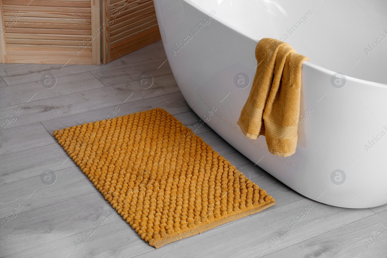 Photo of Soft orange mat on floor near tub in bathroom. Interior design