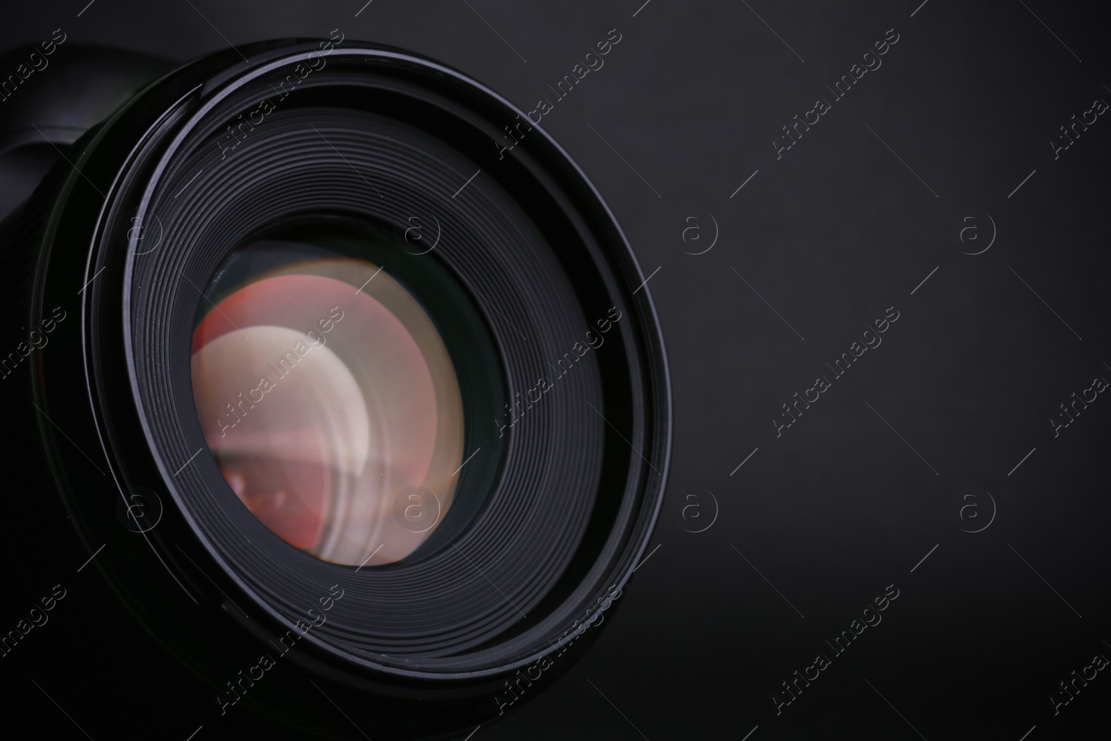 Photo of Modern camera with lens on black background, closeup. Space for text
