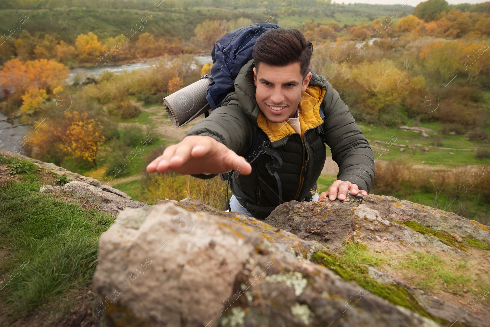 Photo of Hiker with backpack climbing up mountain on autumn day