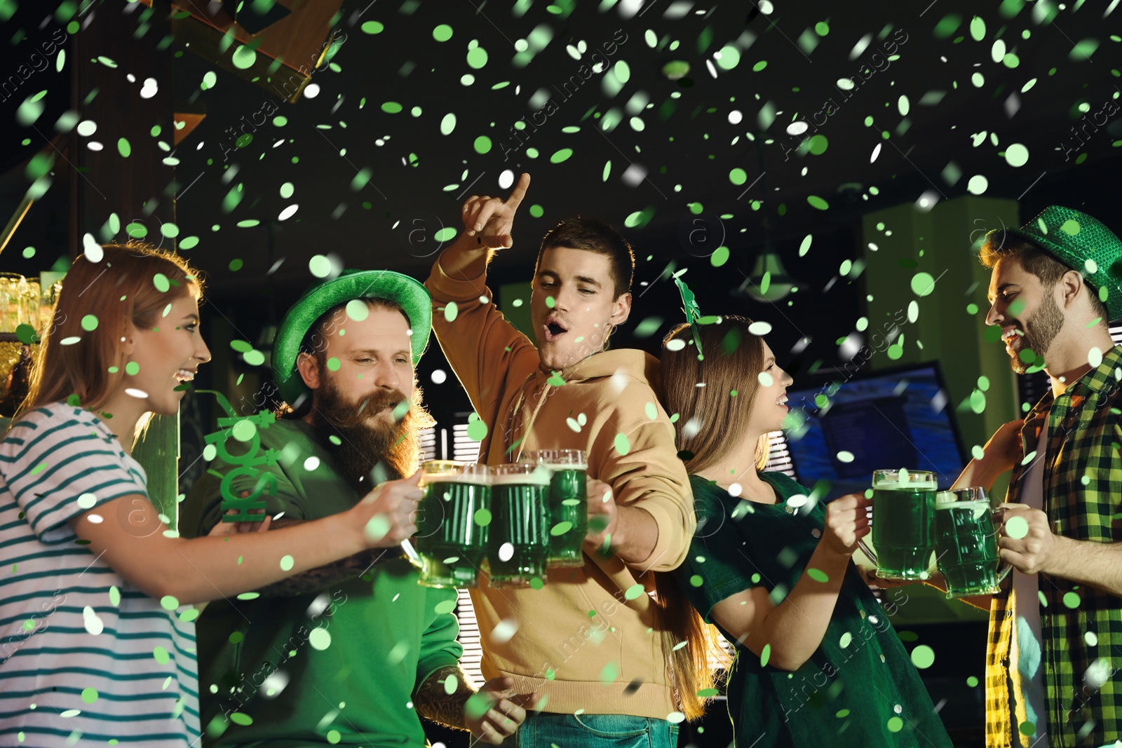 Image of Group of friends toasting with green beer in pub. St. Patrick's Day celebration