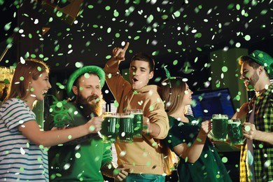 Image of Group of friends toasting with green beer in pub. St. Patrick's Day celebration