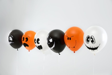 Photo of Spooky balloons for Halloween party on light grey background