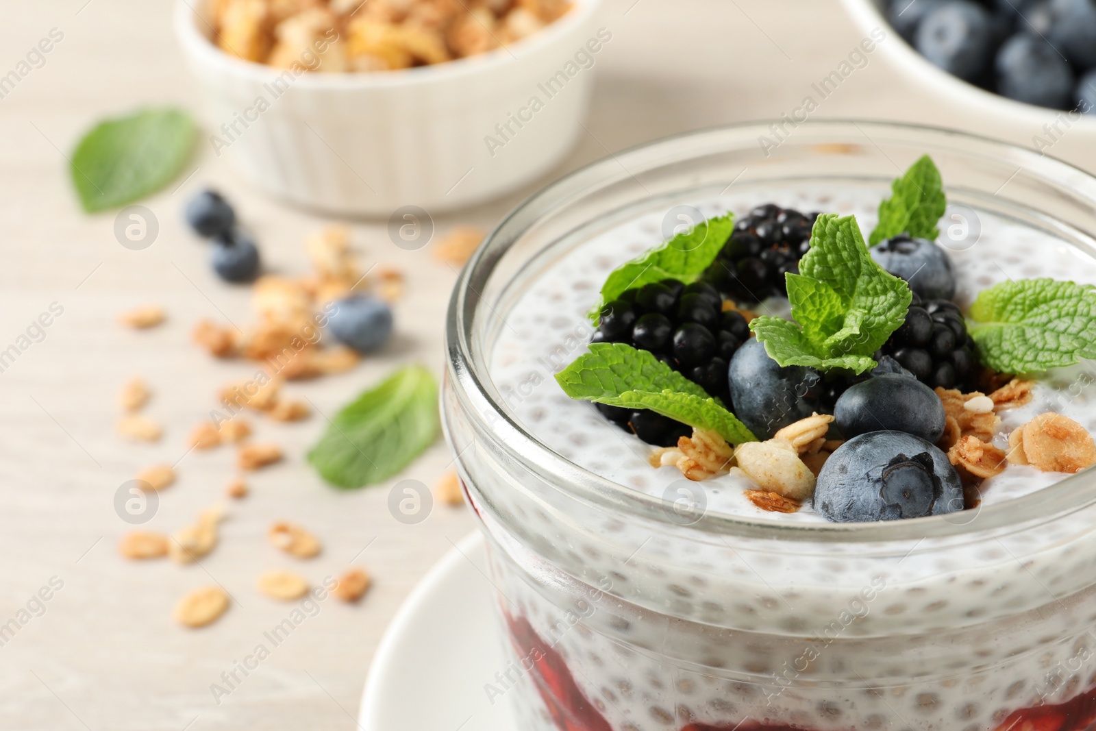 Photo of Delicious chia pudding with berries and granola in jar, closeup