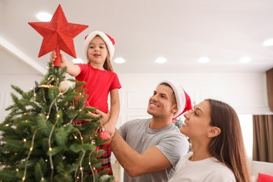 Family decorating Christmas tree with star topper indoors