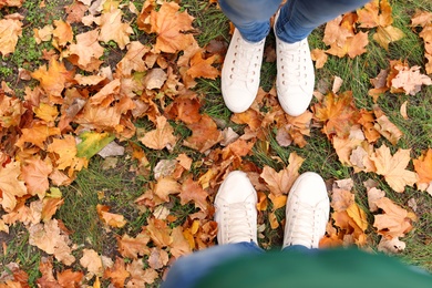 Photo of Couple standing on ground covered with leaves in park, above view. Autumn walk